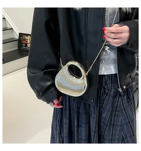 Sac à main argenté métallisé avec poignée ronde et bandoulière chaîne porté par un modèle