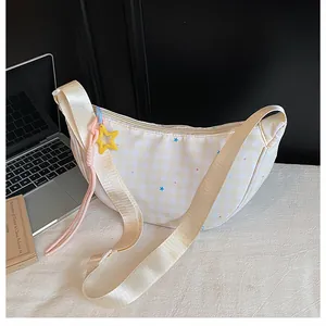 Close-up of cream crescent bag with plaid pattern, star charms and wide shoulder strap