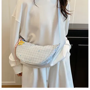Light blue plaid crescent bag shown on model with star charm and soft casual style
