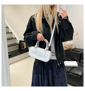 Minimalist white patent leather long handbag shown with shoulder strap on a model