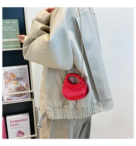 Sac à main rouge en acrylique avec bandoulière chaîne dorée porté par un mannequin