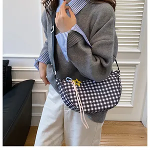 Detail of checkered crescent crossbody bag with star charm and pink woven cord accents