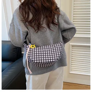 Detail of checkered crescent crossbody bag with star charms and woven cord accessory
