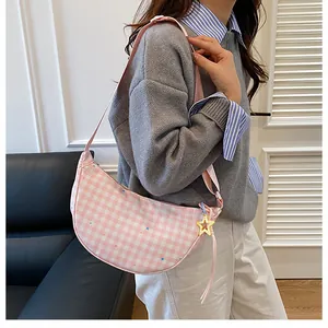 Detail view of pink plaid crescent bag with star patterns and a yellow star pendant charm