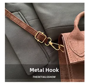 Detailed close-up of brown suede handbag featuring high-quality golden metal hooks