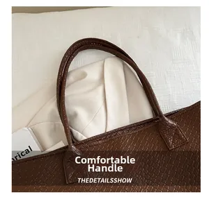 Close-up of brown crocodile pattern tote bag with sturdy handles and fine stitching details