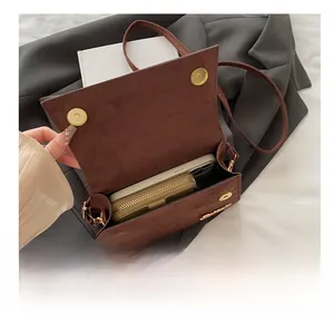 Interior capacity show of brown suede crossbody bag with smartphone and green coin purse