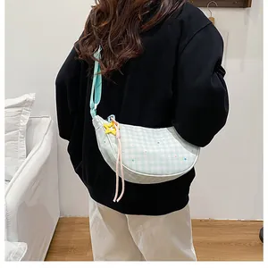 Detail of mint green gingham half-moon crossbody bag with star pendant on model