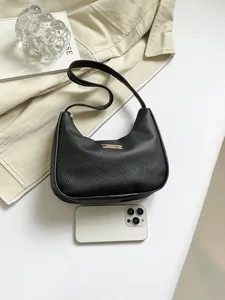 Detailed macro of black litchi texture leather hobo bag with gold metal trim and phone
