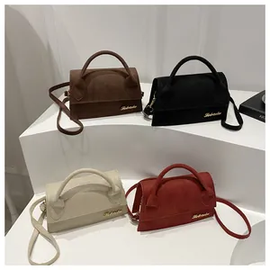 Chic suede crossbody bags in four colors with gold logo on white tiered stand