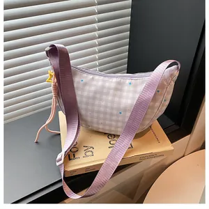 Detail of lavender checkered crescent bag with star motifs and wide woven shoulder strap