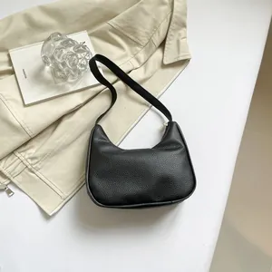 Macro detail of the premium black lychee pattern leather texture on a hobo bag