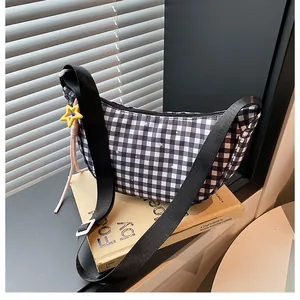 Close-up of black and white plaid half-moon crossbody bag with yellow star charm detail