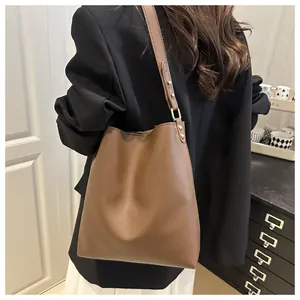 Gros plan du sac seau en cuir marron montrant le grain et la boucle en métal doré