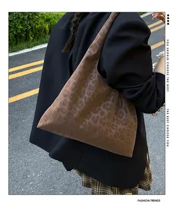 Close-up of leopard print hobo bag in soft faux suede worn by model in city street