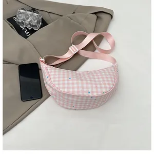 Close-up of pink checkered crescent bag with star prints and adjustable strap