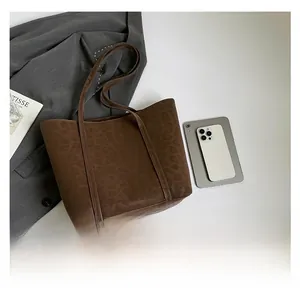 Detail view of large leopard print tote bag with brown straps next to a gray blazer