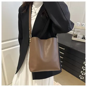 Détail du sac seau en cuir marron avec bandoulière réglable et ferrures en métal doré