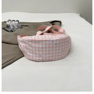 Detail of pink and white checkered crossbody bag with colorful star patterns and strap