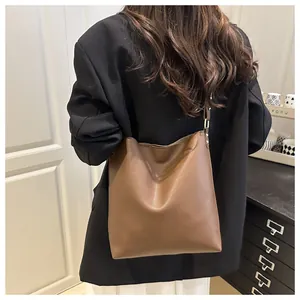 Sac fourre-tout en cuir marron au design spacieux porté sur un blazer noir