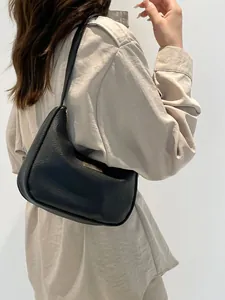 Detail shot of black litchi pattern leather hobo bag with gold metal plaque and side zipper