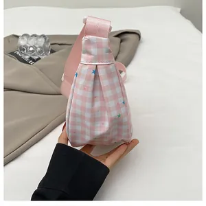 Detail of pink plaid crossbody bag with star prints and adjustable shoulder strap