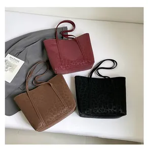 Three leopard print tote bags in burgundy, brown, and black displayed with art book
