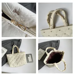 Details einer cremefarbenen Stepptasche mit Schleifenstickerei und Goldreißverschluss