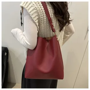 Détail du sac seau bordeaux montrant les ferrures dorées et la bandoulière réglable