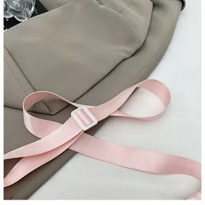 Close-up of pink woven shoulder strap with white plastic buckle on casual crossbody bag