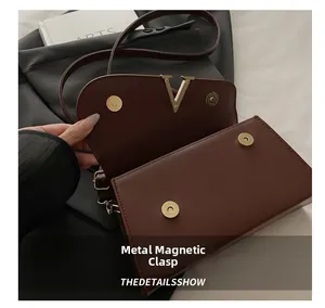 Detailed shot of dark red shoulder bag with magnetic snaps and V-shaped gold hardware