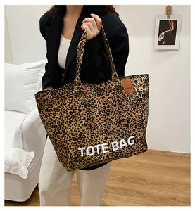 Detail of leopard print tote bag featuring TOTE BAG text and brown leather brand tag