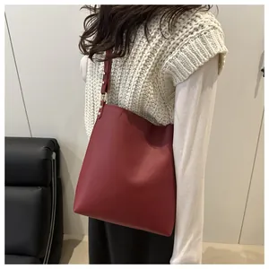 Détail du sac cabas bordeaux en cuir avec bandoulière et finitions dorées claires