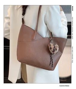 Detail of a brown leather tote bag with lychee texture and leopard print pompom charm