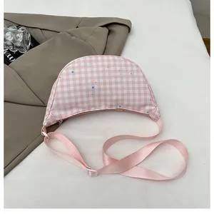 Detail of crescent crossbody bag with pink checkered pattern and star prints