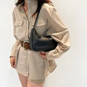 Black litchi pattern leather hobo bag for women with gold logo plaque on beige shirt