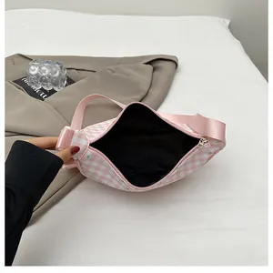 Interior detail of pink plaid crossbody bag showing black lining and smooth metal zipper