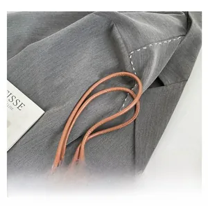 Detailed close-up of brown leather handles with fine stitching on a large tote bag