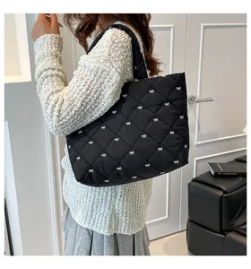 Detail einer großen schwarzen Stepptasche mit weißen Schleifenstickereien am Model