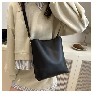Détail d'un sac seau en cuir noir avec ferrures dorées et bandoulière réglable