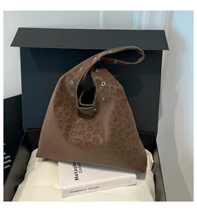 Detail of leopard print tote bag with silver metal eyelets resting on a gift box