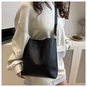 Détail d'un sac seau noir minimaliste avec finition lisse et boucle dorée chic