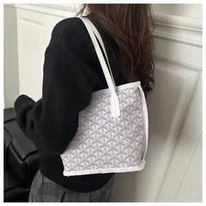Détail du cabas blanc avec motif en Y porté à l'épaule par un mannequin en pull noir