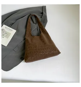 Detailed view of large leopard print tote bag placed on a grey blazer for a chic autumn look