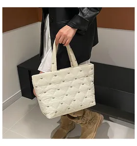 Detail einer cremefarbenen Stepptasche mit brauner Schleifenstickerei und Karomuster