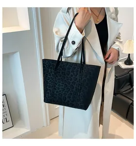 Detail of a large black tote bag with leopard print texture worn by a model