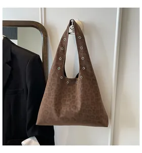 Detail of leopard print tote bag featuring silver metal grommets and suede texture