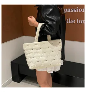Detailansicht der cremefarbenen Stepptasche mit Schleifenstickerei und weichem Griff