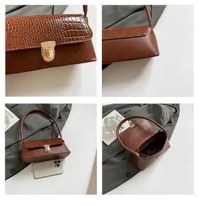 Detail view of brown crocodile-embossed bag texture, gold hardware and internal storage