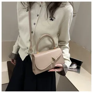 Detail of apricot faux leather handbag with golden V buckle and adjustable strap